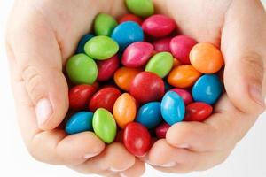 Multicolored candies in the hands of a child on a white isolated background photo