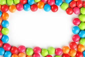 Frame of multi-colored candies close up. Rainbow colored dragee multicolored glaze on a white background photo