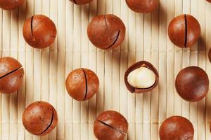 Flat composition with Australian macadamia nuts on bamboo light background. Patterns, repetitions photo