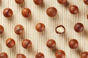 Flat composition with Australian macadamia nuts on bamboo light background. Patterns, repetitions photo