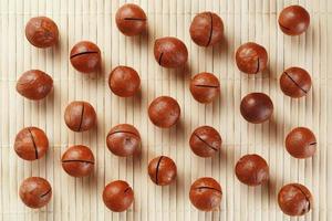 Flat composition with Australian macadamia nuts on bamboo light background. Patterns, repetitions photo