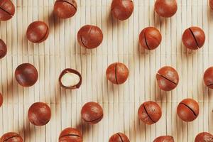 Flat composition with Australian macadamia nuts on bamboo light background. Patterns, repetitions photo