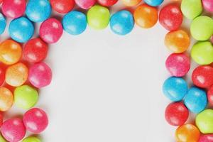 Frame of multi-colored candies close up. Rainbow colored dragee multicolored glaze on a white background photo