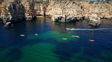 Aerial drone view of boats and kayaks in the Atlantic Ocean, Lagos, Algarve, Portugal. Exploring caves and tunnels. Travel and adventure. Holidays and Vacations. Beautiful blue color from the ocean.