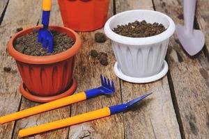 Flower pots and set decorative gardening tools shovel, rake and pitchfork on a wooden background. photo