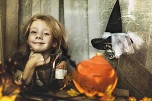 Halloween concept. Little toddler girl in a witch costume behind a glass window. Trick or Treat photo