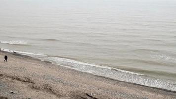 vagues par une journée venteuse. homme marche sur la plage. video