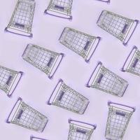 Pattern of many small shopping carts on a violet background. Minimalism flat lay top view photo