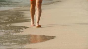 turister som går barfota på våt sand nai harn beach, phuket video