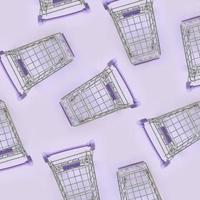 Pattern of many small shopping carts on a violet background. Minimalism flat lay top view photo