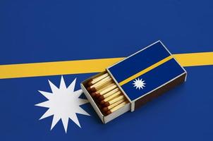 Nauru flag  is shown in an open matchbox, which is filled with matches and lies on a large flag photo
