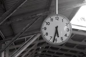 A white vintage round clock hanging on the roof of a train station.