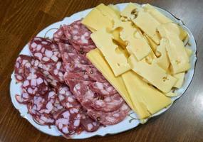 Sliced sausage and cheese are on plate. photo