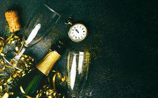 Happy New Year. Champagne bottle with two glasses,golden streamers,sparkling glitter and antique clock with copy space. New Years Eve celebration concept background photo