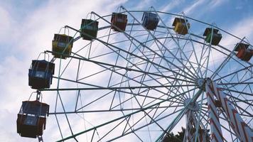 Colorful ferris wheels in the amusement park on a background of blue sky with clouds. Toned image. Bottom view photo