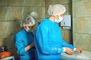 Adult woman doctor preparing for the operation with an assistant photo