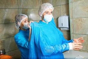 joven doctora preparándose para la operación con un asistente foto