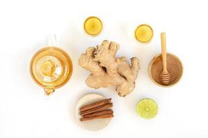 Top view of a cup of tea with ginger root, lime, cinnamon and teapot on white background. Health drink concept. photo