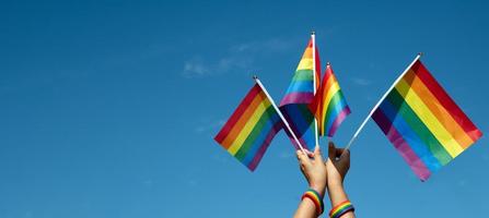 Look up view of rainbow flag, LGBT simbol, against clear bluesky background, soft and  selective focus, concept for LGBT celebration in pride month, June, around the world, copy space. photo