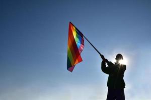 Look up view of rainbow flag, LGBT simbol, against clear bluesky background, soft and  selective focus, concept for LGBT celebration in pride month, June, around the world, copy space. photo