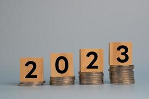 cubo madera año nuevo 2023 puesta en marcha inversión nuevos negocios y economía financiera crecimiento fila de monedas.ahorro de dinero y concepto de plan financiero para inversión en el año nuevo 2023. foto