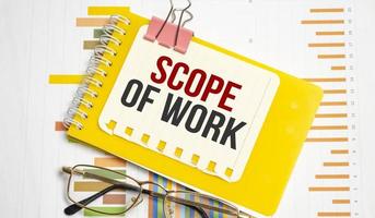 Scope Of Work words on yellow sticker with charts and glasses photo