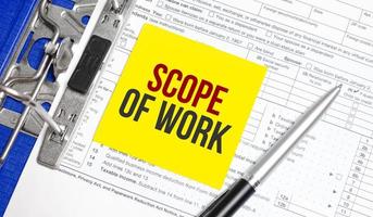 Scope Of Work words on yellow sticker with tax forms and pen photo