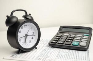 Top view tax form 1040 with pen, calculator and black alarm clock. tax time. financial document. photo