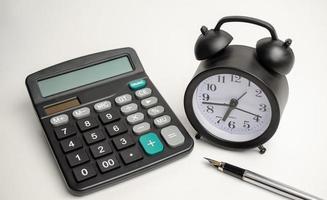 alarm clock with calculator and pen on white background photo