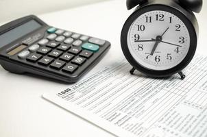 formulario de impuestos con reloj, bolígrafo y calculadora sobre fondo blanco. concepto de negocio. foto