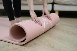 primer plano de la mano de una mujer joven sosteniendo una alfombra de fitness, entrenamiento en casa y el concepto de un estilo de vida saludable. foto