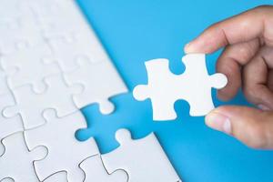 White jigsaw in the hands, The correct solution. Teamwork, Solving and completing the task. Last piece of jigsaw puzzle. Assembling jigsaw puzzle pieces. photo