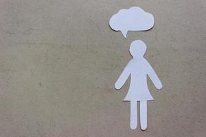 The silhouette of a woman in a dress made of white paper, cut by hand. With speech-bubble on right side of the photo and with copy space