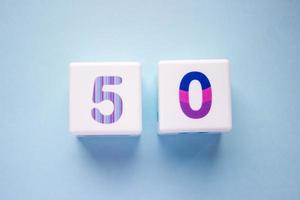 Close-up photo of a white plastic cubes with a colorful number 50 on a blue background. Object in the center of the photo