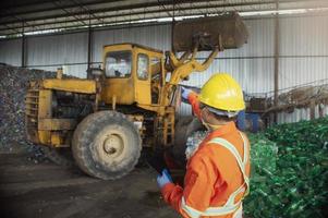 engineer worker in protective uniform and with hardhat using tablet for checking working. recycling industry. photo