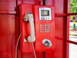 el viejo teléfono con cable rojo en el pasado, es como volver al pasado donde la gente solía usar teléfonos públicos. foto