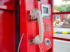 el viejo teléfono con cable rojo en el pasado, es como volver al pasado donde la gente solía usar teléfonos públicos. foto