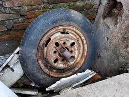 old car rims, flat and cracked, rusted through the brick wall. photo