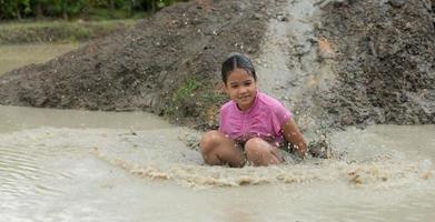 Little girls have fun playing in the mud in the community fields photo