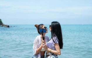 parejas lgbt que viajan por asia, nadan felices en la playa de arena con el hermoso mar azul foto