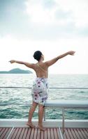 An Asian girl on a yacht stand to receive the fresh air from the sea photo