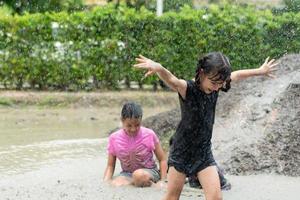 Little girls have fun playing in the mud in the community fields