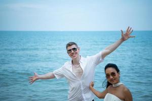 Interracial couple with the joy of traveling to the beautiful blue sea like the paradise photo