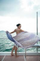 An Asian girl on a yacht stand to receive the fresh air from the sea with a shawl that flew in beautiful waves photo
