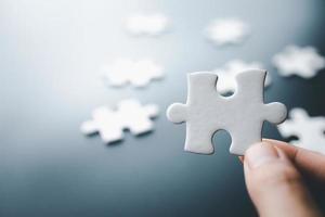 White jigsaw in the hands, The correct solution. Teamwork, Solving and completing the task. Last piece of jigsaw puzzle. Assembling jigsaw puzzle pieces. photo