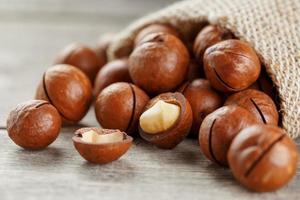 Macadamia nut on a wooden table in a bag, closeup, top view photo