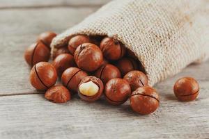 Macadamia nut on a wooden table in a bag, closeup, top view photo