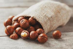 Macadamia nut on a wooden table in a bag, closeup, top view photo