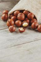 Macadamia nut on a wooden table in a bag, closeup, top view photo