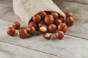 Macadamia nut on a wooden table in a bag, closeup, top view photo